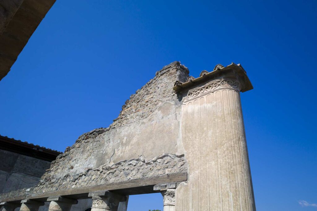 Decorated column at Pompeii's Stabian Baths with architectural details and blue sky.