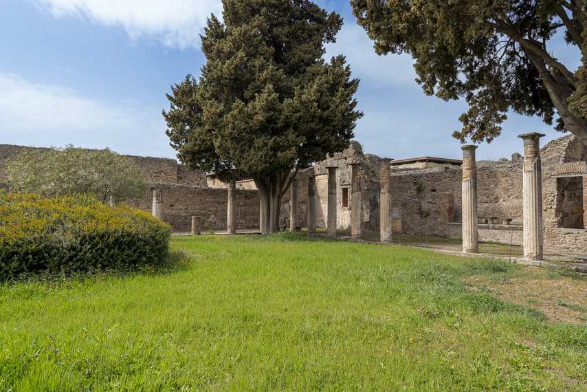 Colonnade of the House of the Faun in Pompeii with lawn and cypress trees